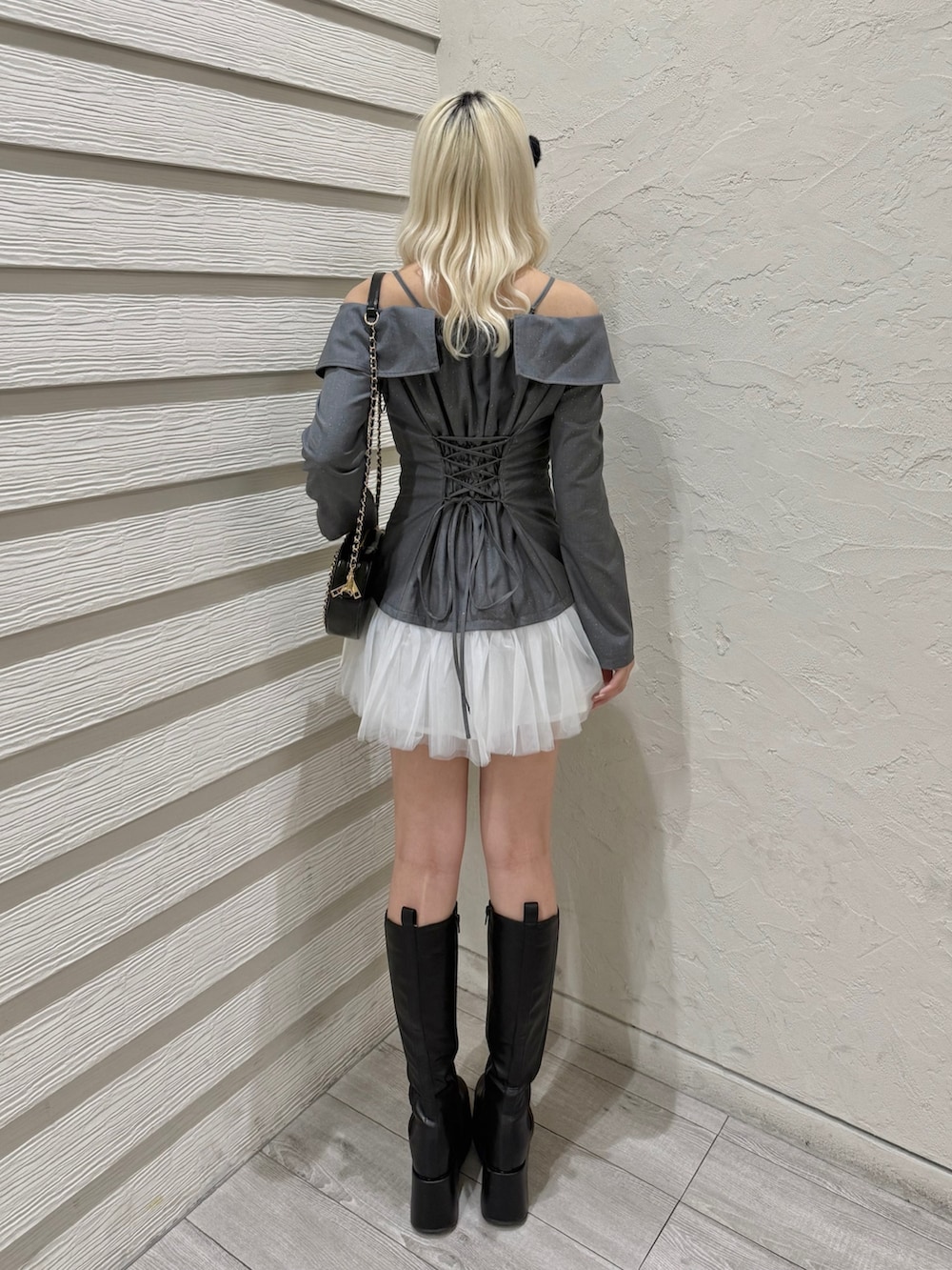 グレー系のワンピース、ブラック系のショルダーバッグ、ブラック系のブーツを着用したレディースの冬コーディネートの3枚目の写真