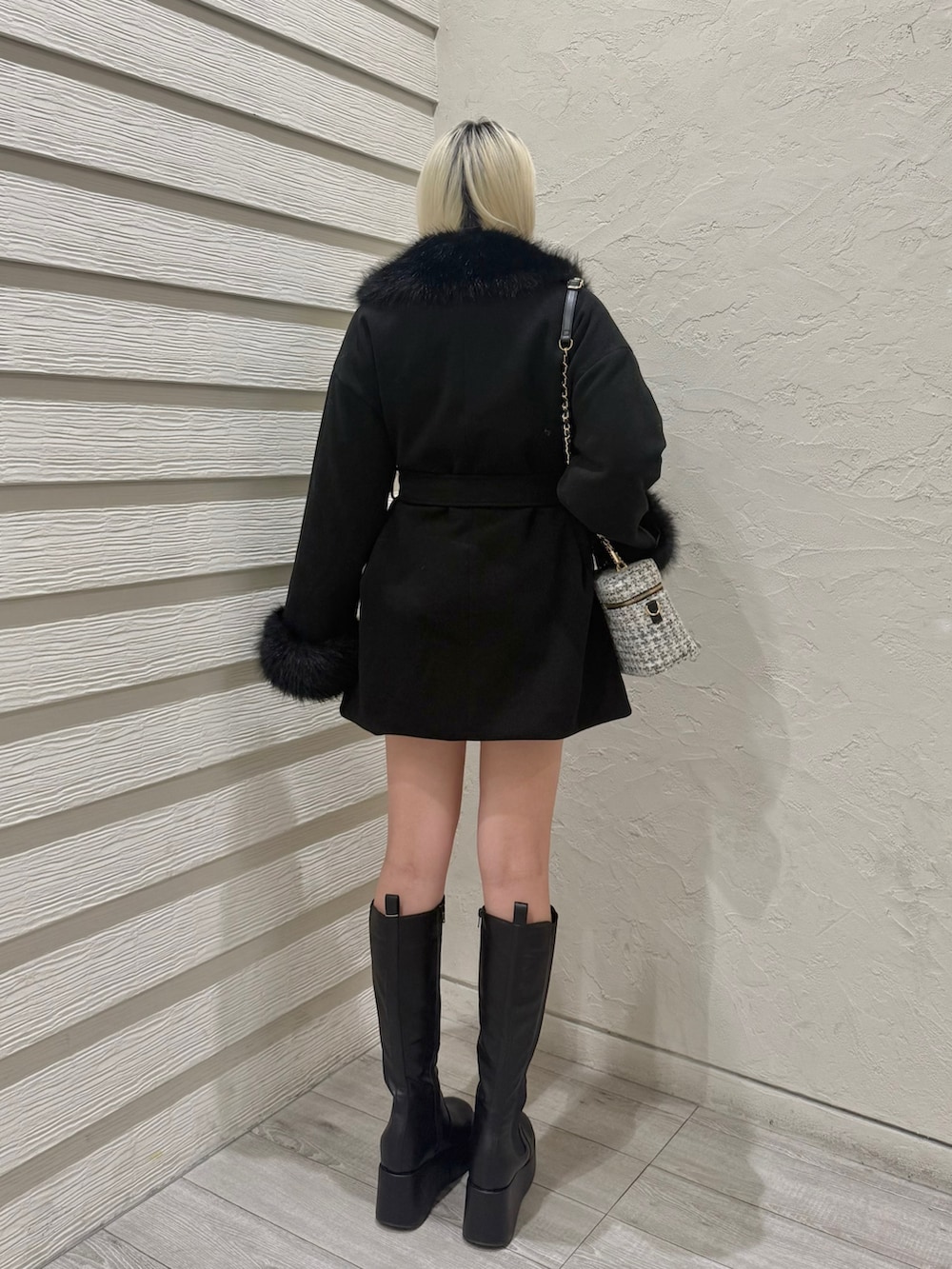 ホワイト系のニット/セーター、ブラック系のステンカラーコート、ホワイト系のショルダーバッグを着用したレディースの冬コーディネートの3枚目の写真