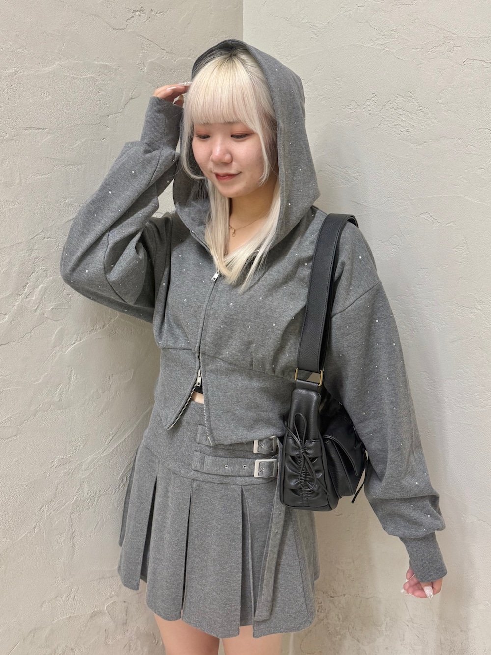 ブラック系のショルダーバッグ、グレー系のパーカー、グレー系のスカートを着用したレディースの秋コーディネートの6枚目の写真