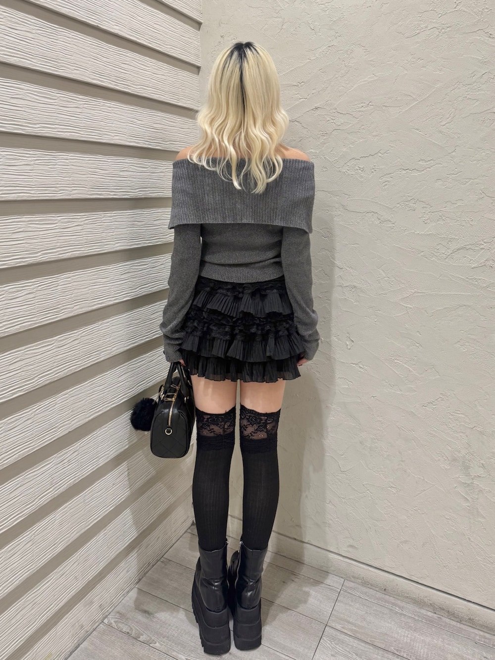 グレー系のニット/セーター、ブラック系のスカート、ブラック系のボストンバッグを着用したレディースの冬コーディネートの3枚目の写真