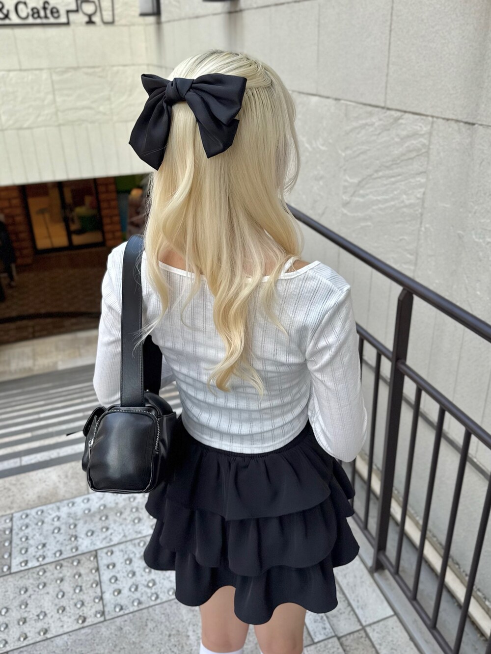 ブラック系のスカート、ホワイト系のTシャツ/カットソー、ブラック系のショルダーバッグを着用したレディースの春コーディネートの5枚目の写真