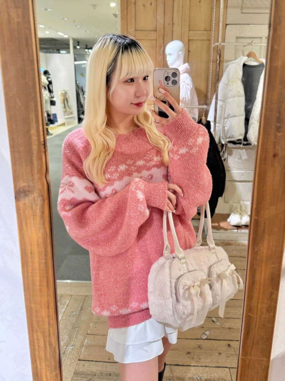 ホワイト系のショルダーバッグ、ホワイト系のスカート、レッド系のニット/セーターを着用したレディースの冬コーディネートの2枚目の写真