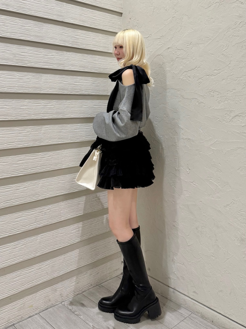 グレー系のTシャツ/カットソー、ブラック系のスカート、ホワイト系のトートバッグを着用したレディースの冬コーディネートの2枚目の写真