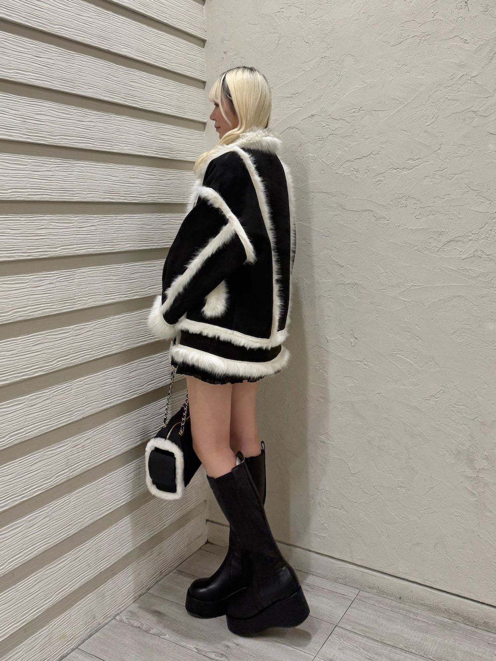 ブラック系のブーツ、ブラック系のボストンバッグ、ブラック系のスカートを着用したレディースの冬コーディネートの2枚目の写真