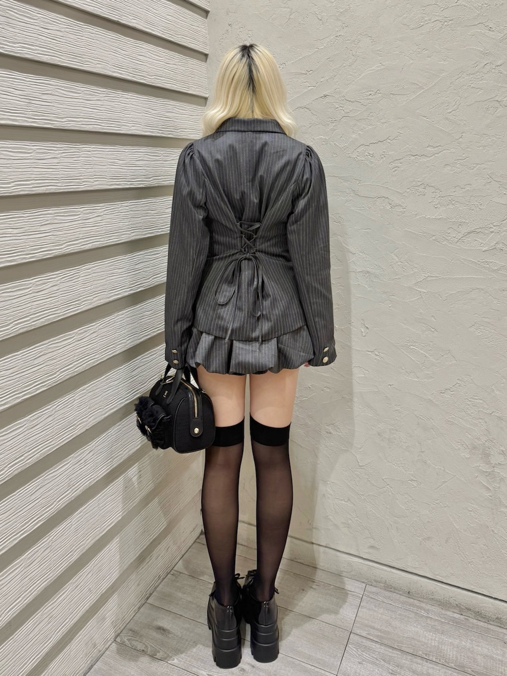 グレー系のテーラードジャケット、グレー系のスカート、ブラック系のショルダーバッグを着用したレディースの冬コーディネートの3枚目の写真