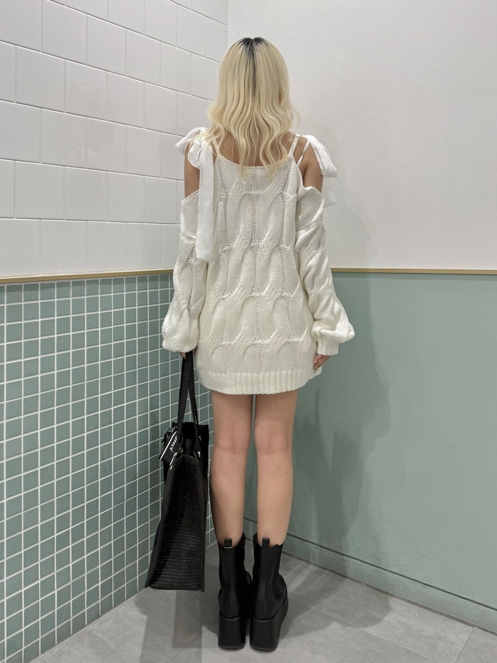 ブラック系のトートバッグ、ブラック系のブーツ、ホワイト系のワンピースを着用したレディースの冬コーディネートの3枚目の写真