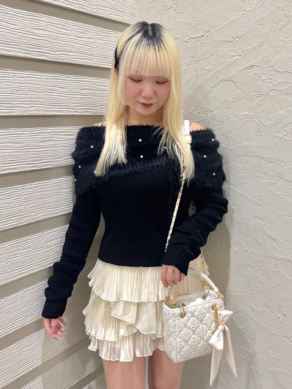 ブラック系のニット/セーター、ホワイト系のスカート、ホワイト系のショルダーバッグを着用したレディースの冬コーディネートの4枚目の写真