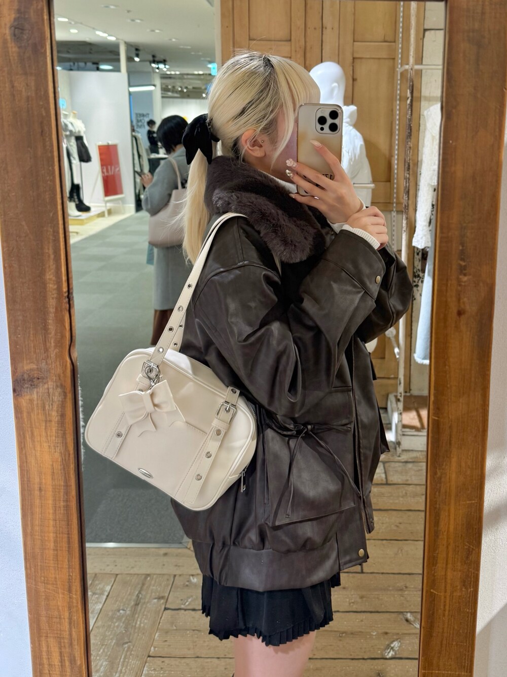 ブラウン系のブルゾン、ブラック系のワンピース、ホワイト系のニット/セーターを着用したレディースの冬コーディネートの3枚目の写真