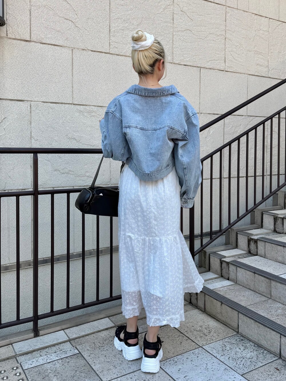 ブルー系のデニムジャケット、ブラック系のショルダーバッグ、ホワイト系のワンピースを着用したレディースの春コーディネートの2枚目の写真