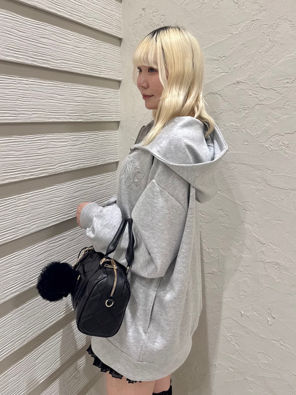 グレー系のパーカー、ブラック系のキャミソール、ブラック系のスカートを着用したレディースの冬コーディネートの6枚目の写真