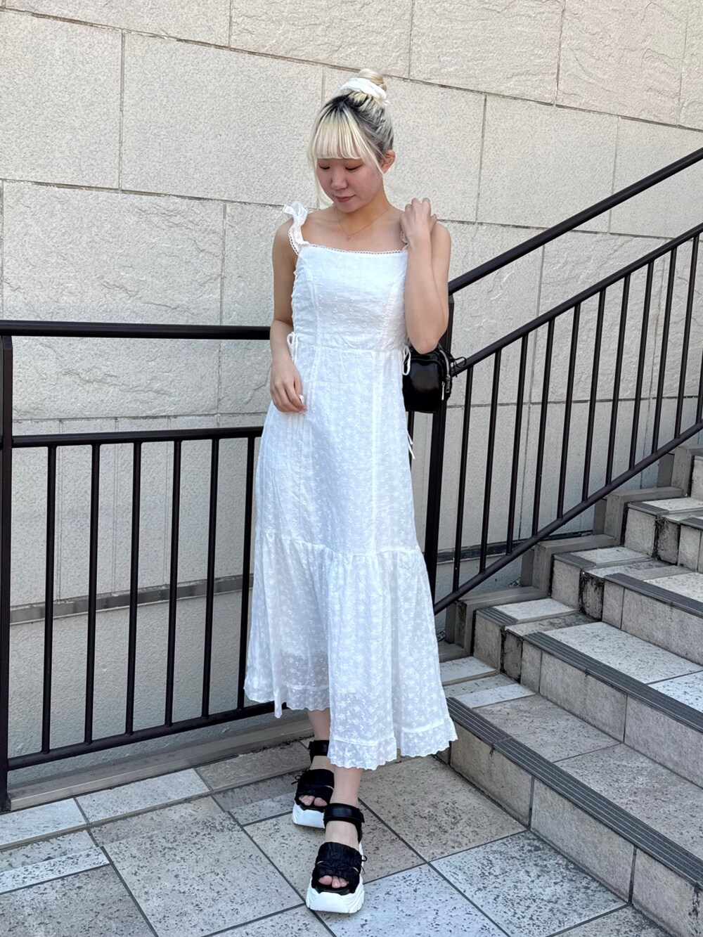 ブルー系のデニムジャケット、ブラック系のショルダーバッグ、ホワイト系のワンピースを着用したレディースの春コーディネートの4枚目の写真