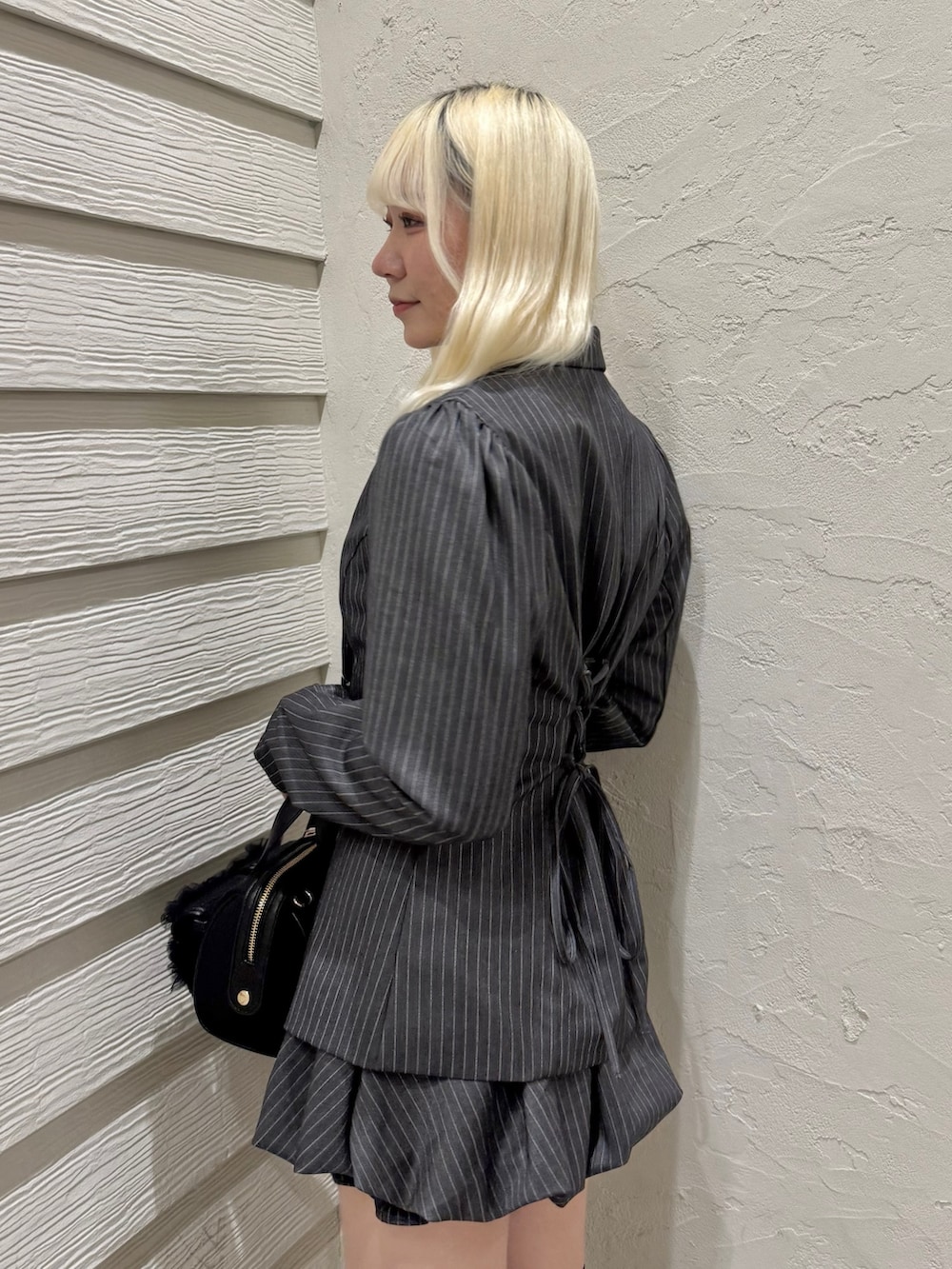 グレー系のテーラードジャケット、グレー系のスカート、ブラック系のショルダーバッグを着用したレディースの冬コーディネートの5枚目の写真