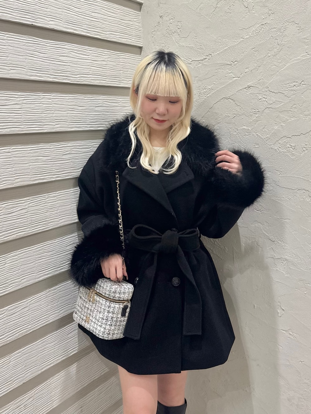 ホワイト系のニット/セーター、ブラック系のステンカラーコート、ホワイト系のショルダーバッグを着用したレディースの冬コーディネートの4枚目の写真