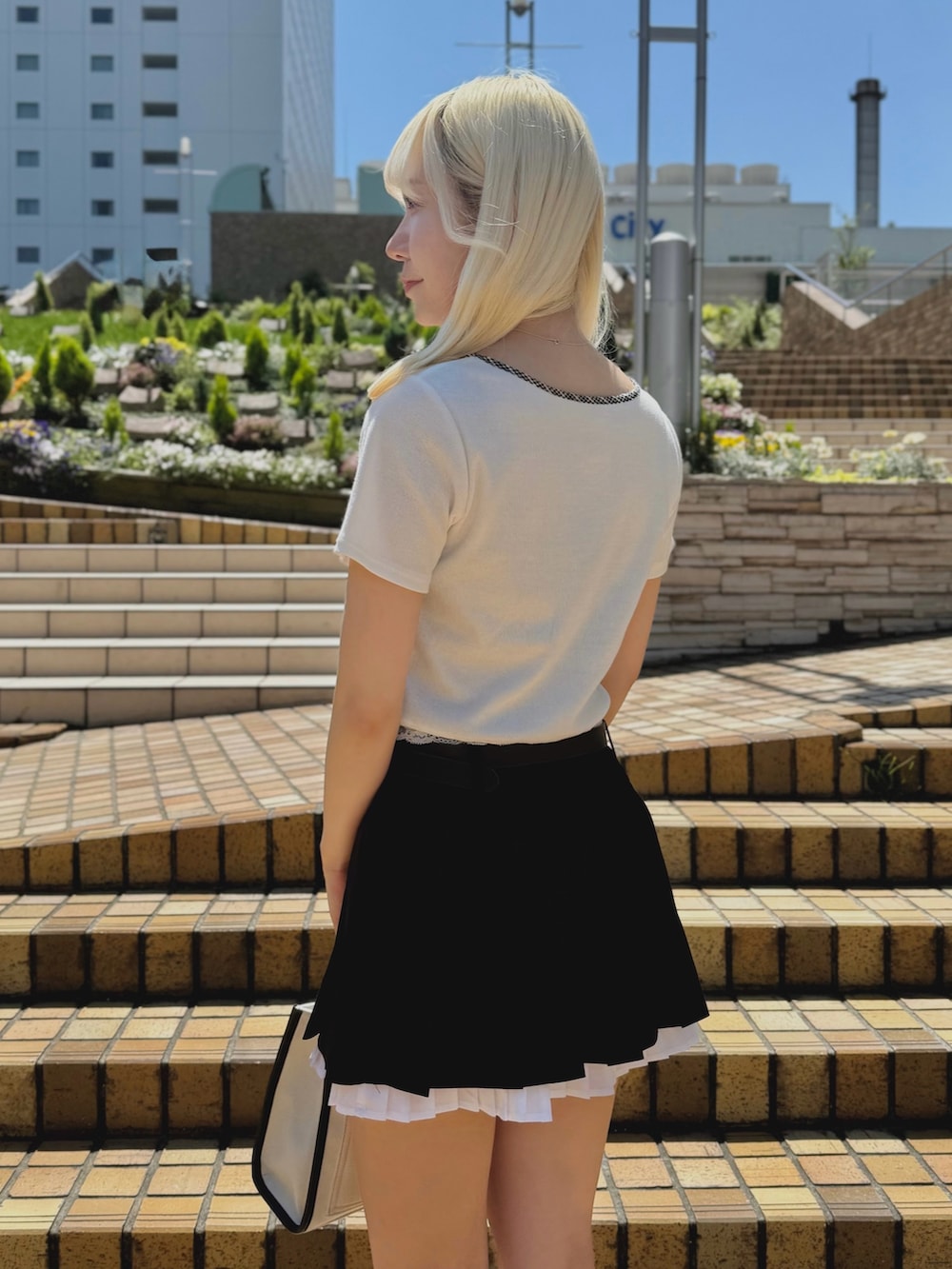 ブラック系のスカート、ホワイト系のTシャツ/カットソー、ホワイト系のトートバッグを着用したレディースの夏コーディネートの4枚目の写真