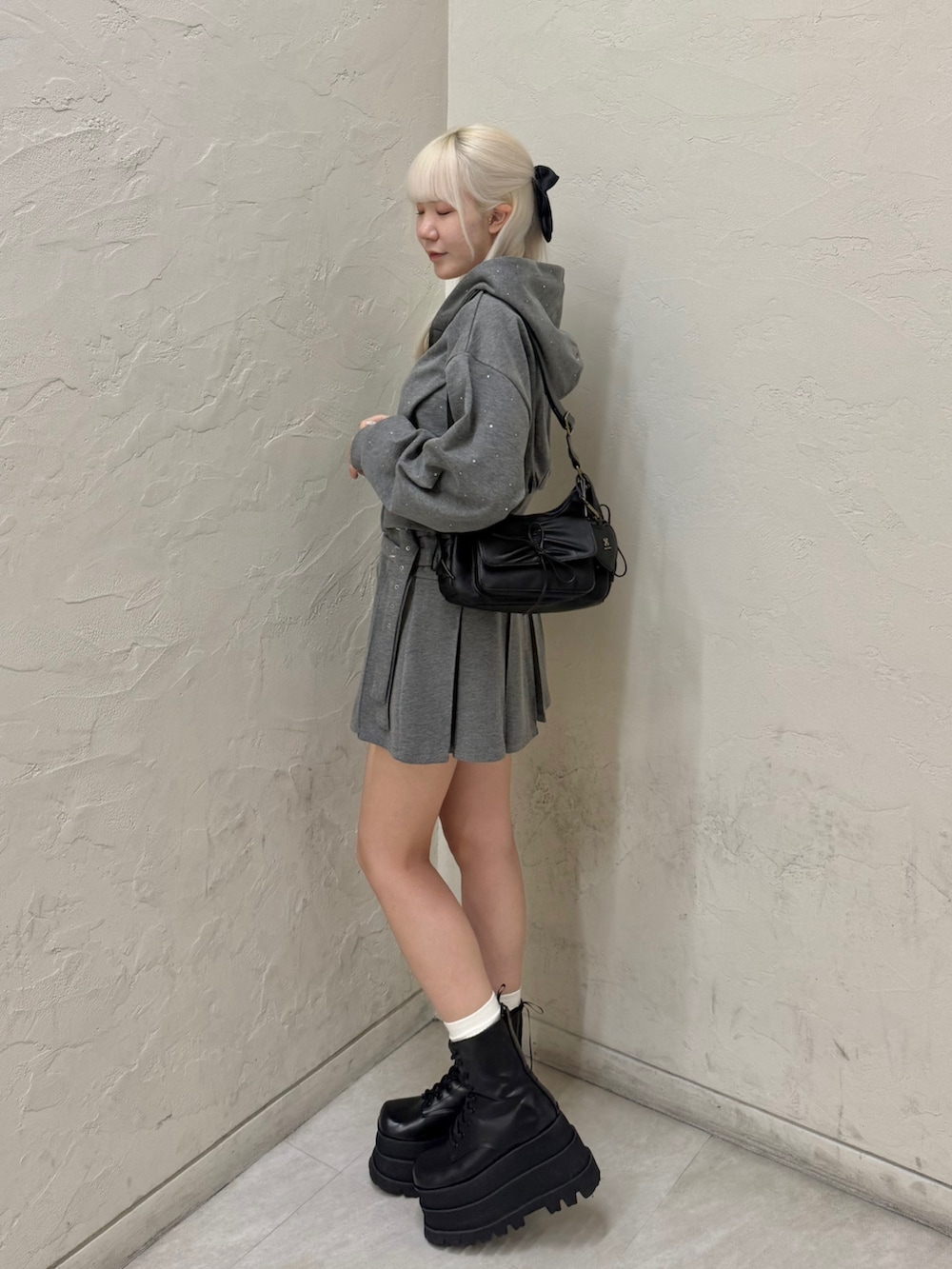 ブラック系のショルダーバッグ、グレー系のパーカー、グレー系のスカートを着用したレディースの秋コーディネートの3枚目の写真