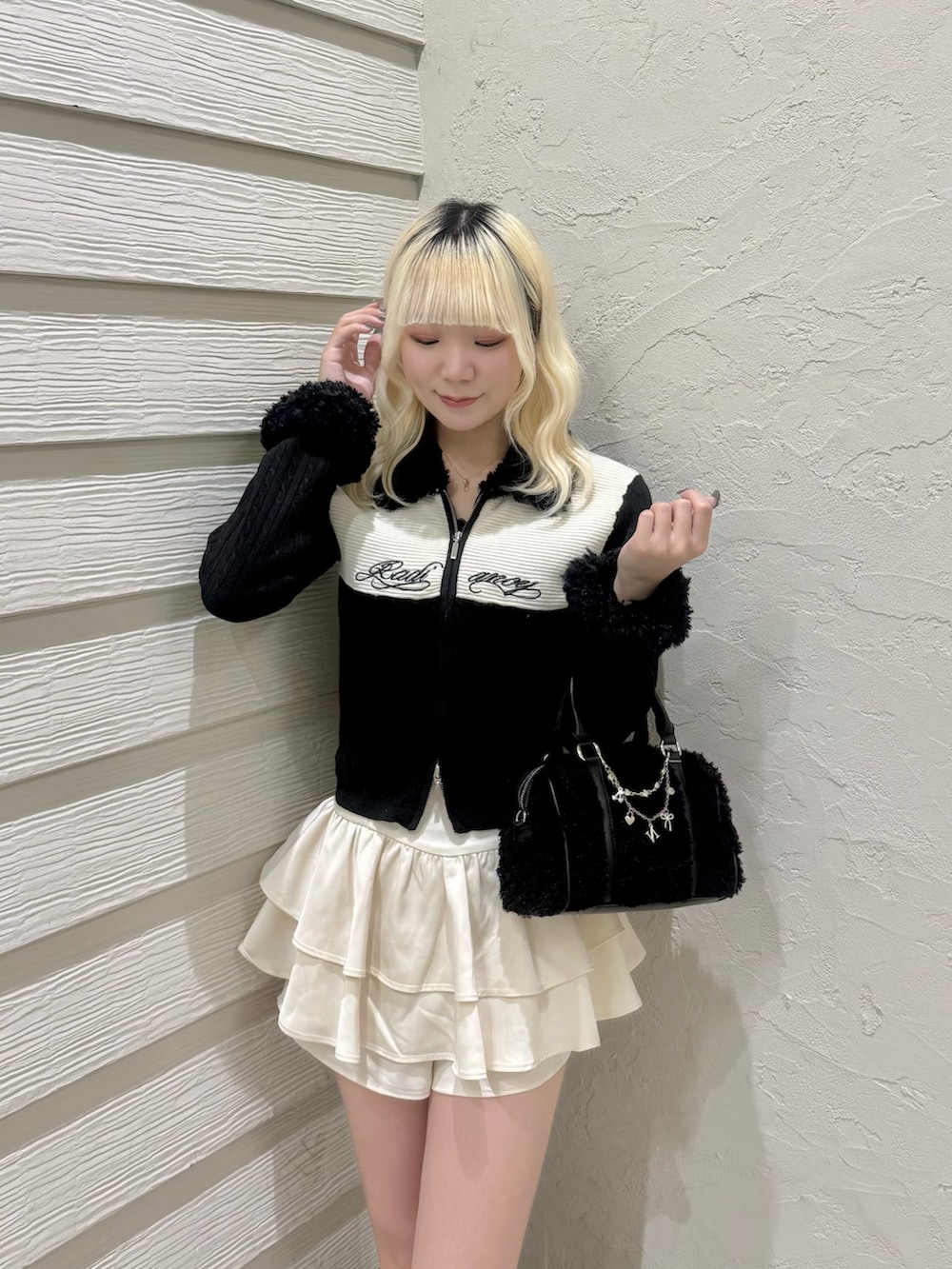 ブラック系のニット/セーター、ホワイト系のスカート、ブラック系のショルダーバッグを着用したレディースの秋コーディネートの5枚目の写真