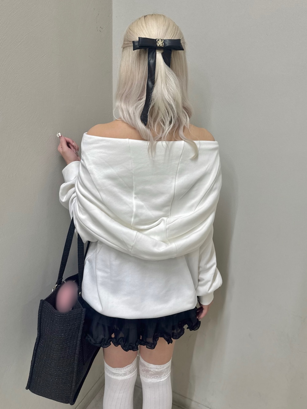 ホワイト系のパーカー、ブラック系のトートバッグ、ブラック系のスカートを着用したレディースの春コーディネートの6枚目の写真