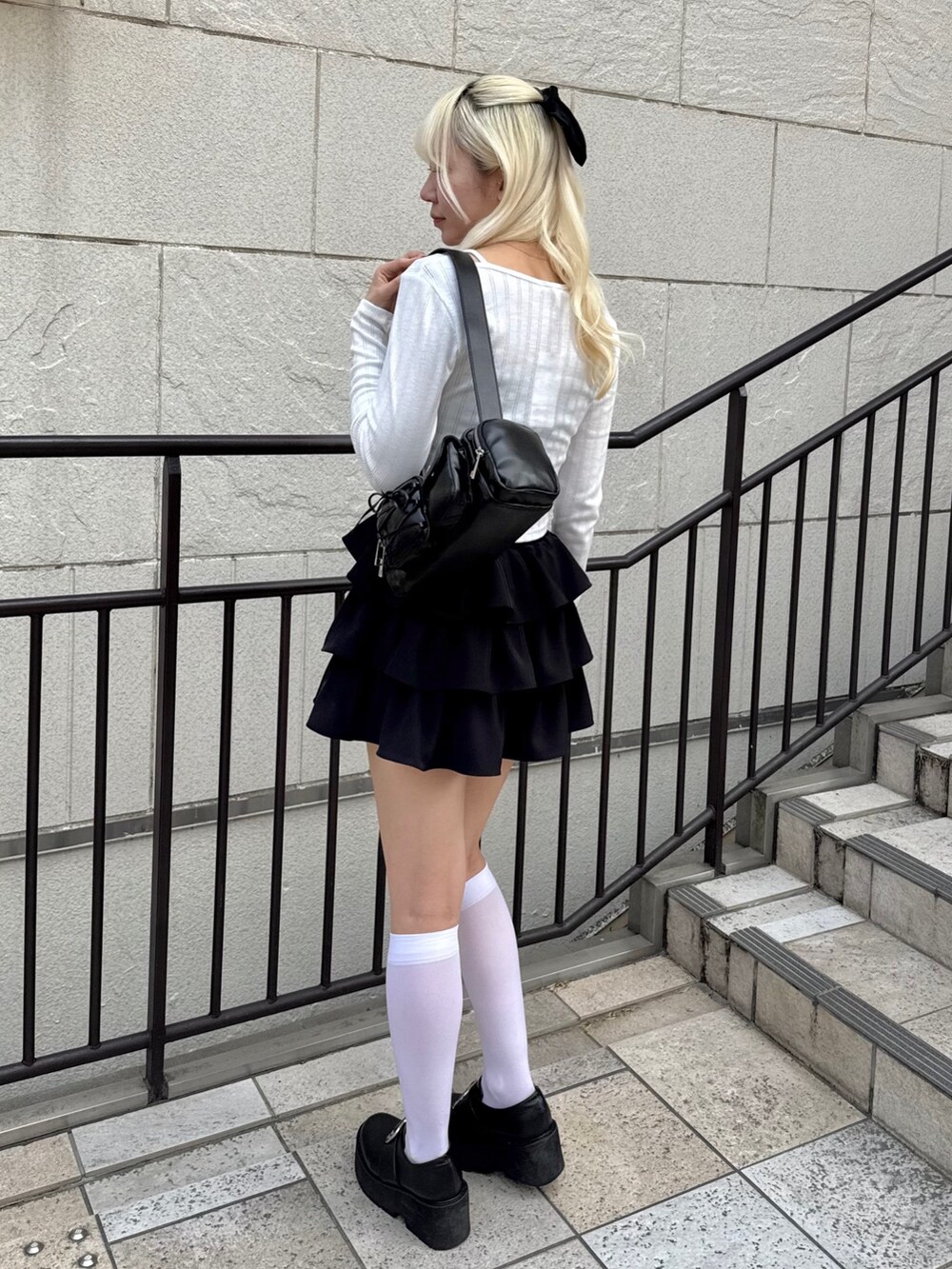 ブラック系のスカート、ホワイト系のTシャツ/カットソー、ブラック系のショルダーバッグを着用したレディースの春コーディネートの2枚目の写真