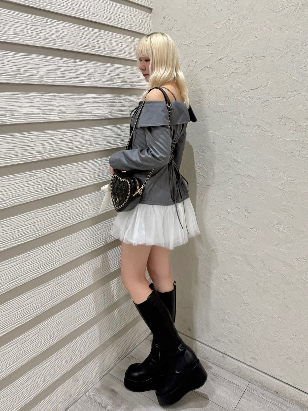 グレー系のワンピース、ブラック系のショルダーバッグ、ブラック系のブーツを着用したレディースの冬コーディネートの2枚目の写真