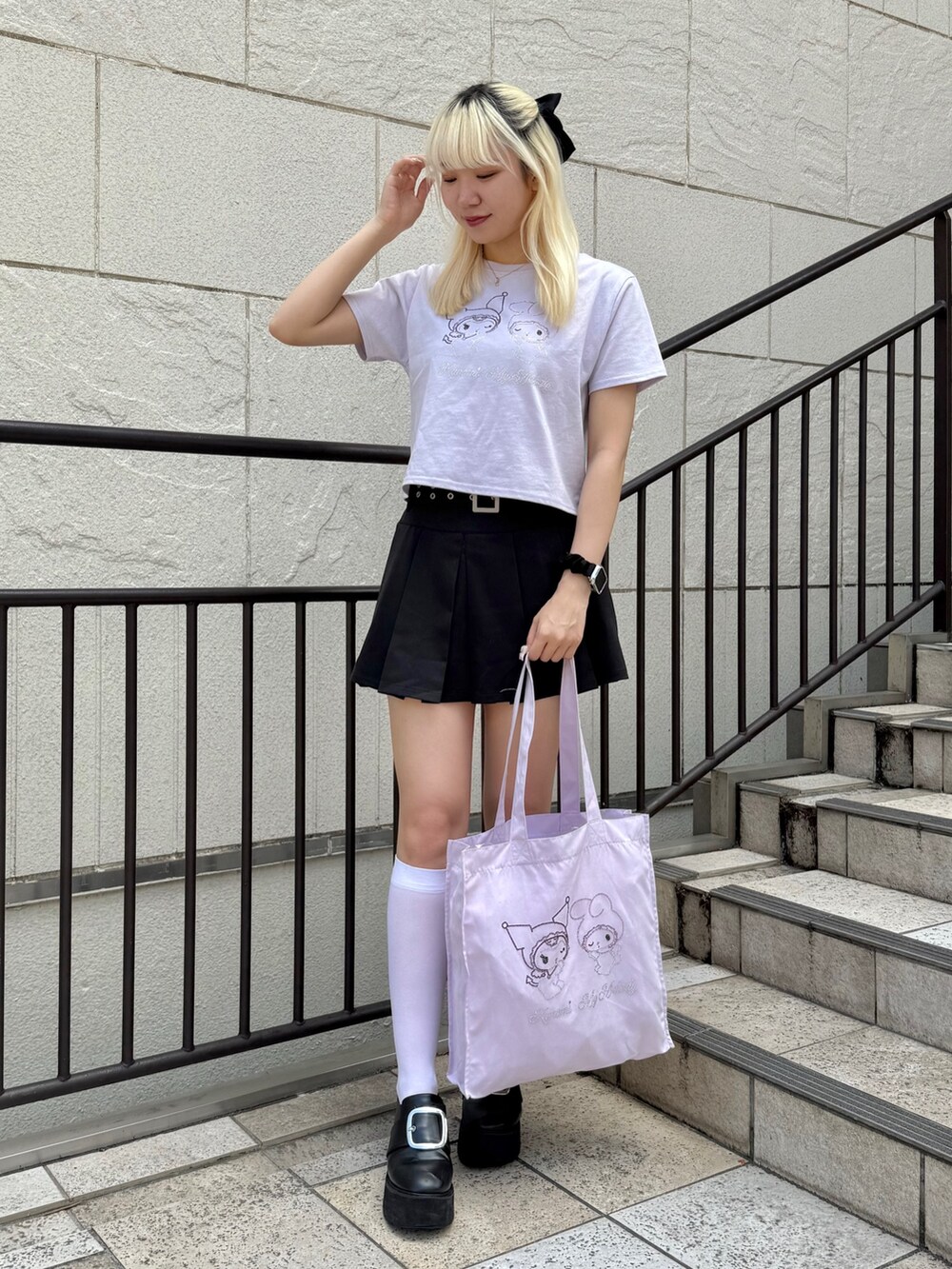 パープル系のトートバッグ、パープル系のTシャツ/カットソー、ブラック系のスカートを着用したレディースの夏コーディネートの2枚目の写真