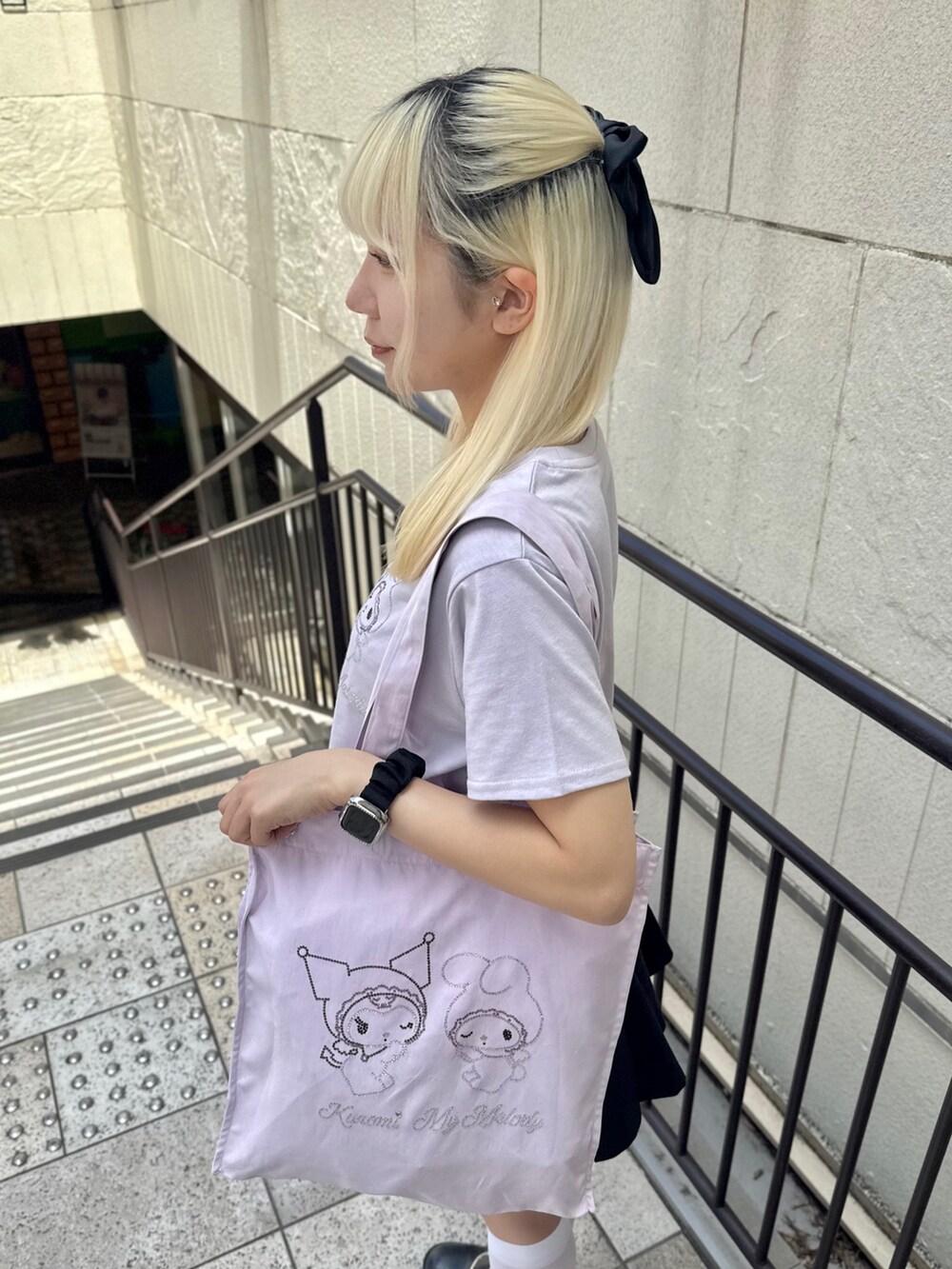 パープル系のトートバッグ、パープル系のTシャツ/カットソー、ブラック系のスカートを着用したレディースの夏コーディネートの6枚目の写真