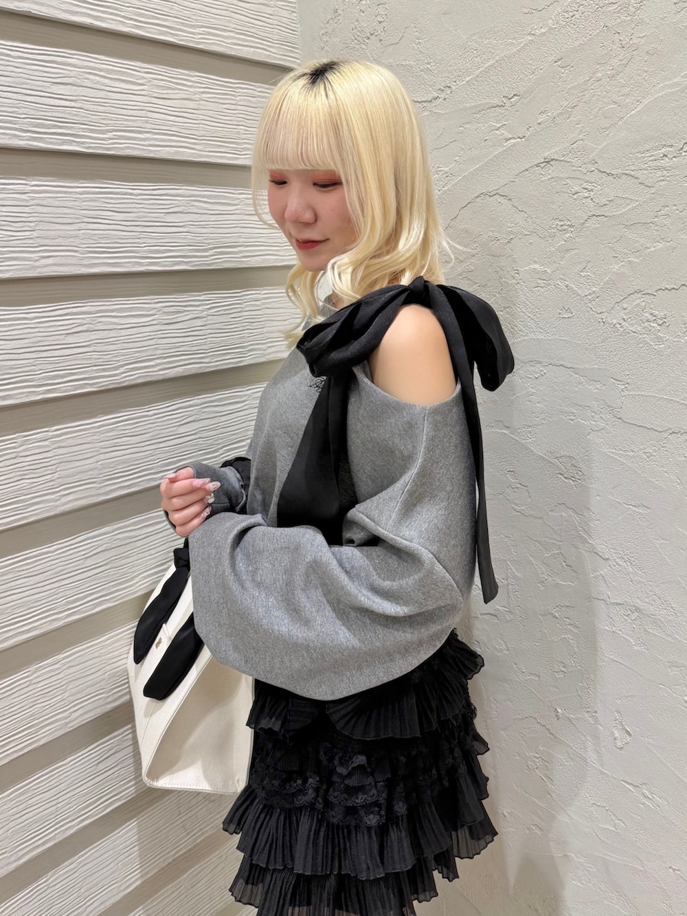 グレー系のTシャツ/カットソー、ブラック系のスカート、ホワイト系のトートバッグを着用したレディースの冬コーディネートの5枚目の写真