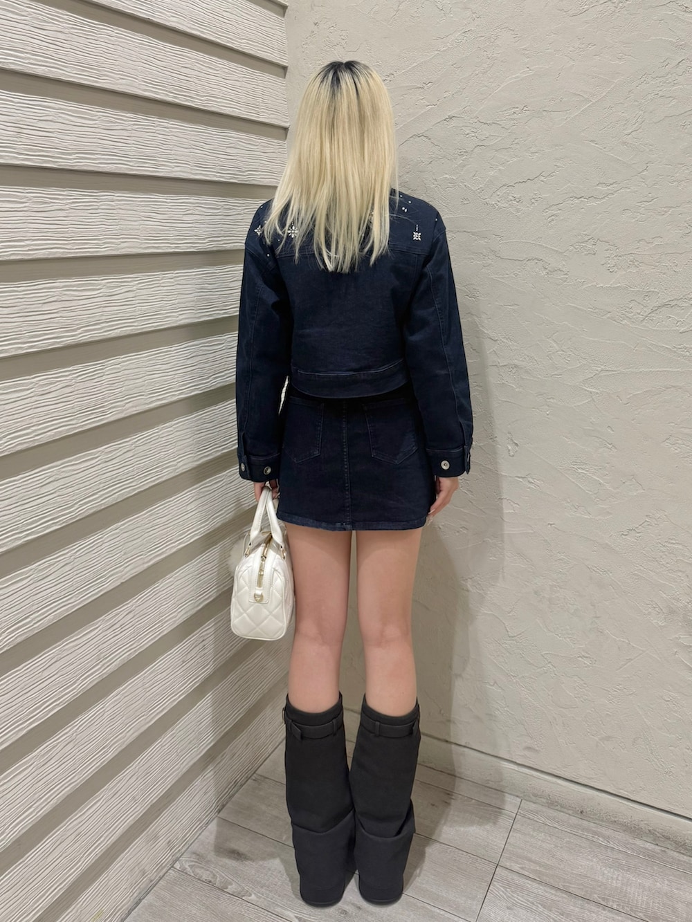 ブルー系のデニムジャケット、ブルー系のデニムスカート、ホワイト系のボストンバッグを着用したレディースの冬コーディネートの3枚目の写真