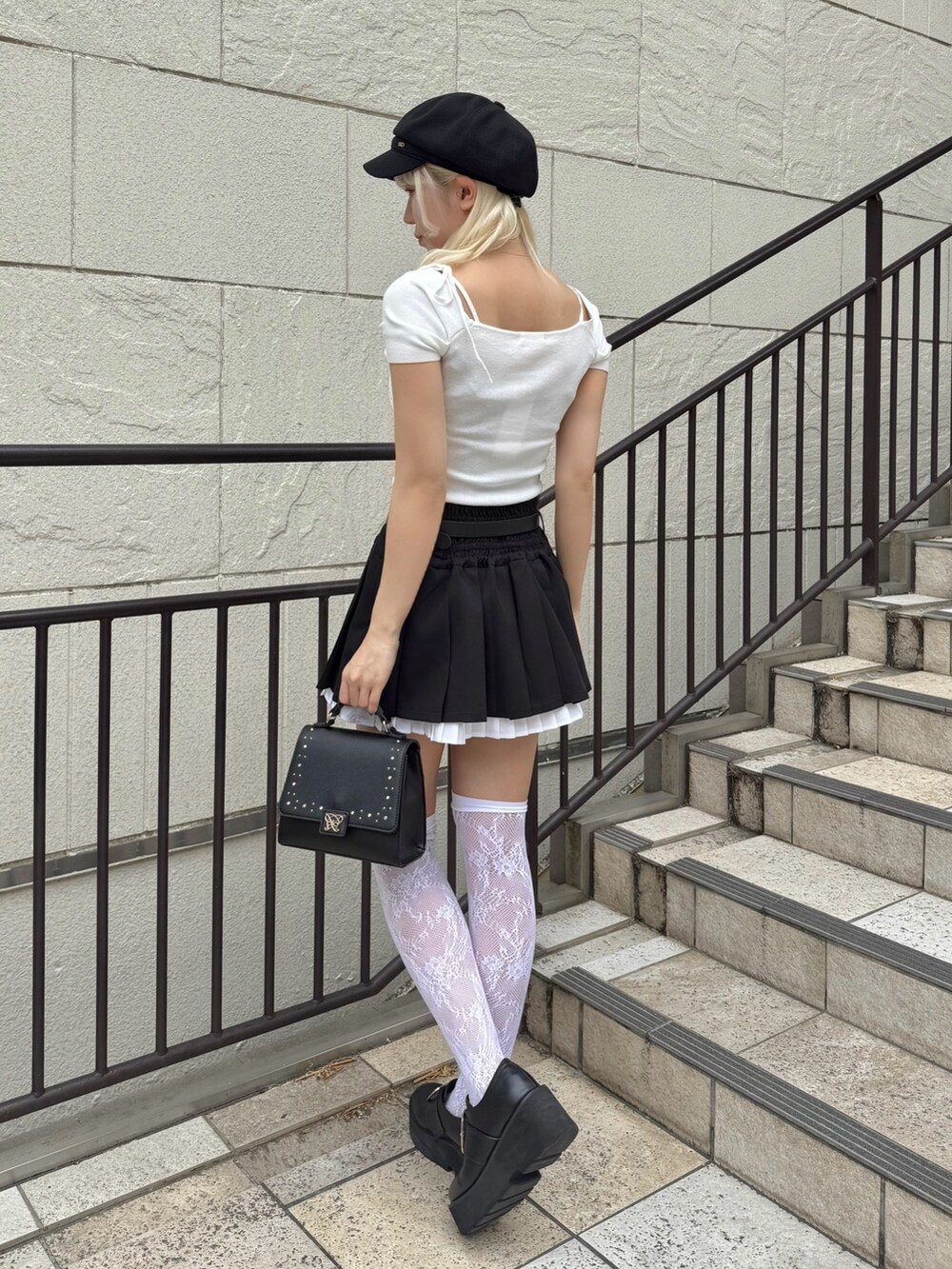 ブラック系のスカート、ホワイト系のTシャツ/カットソー、ブラック系のショルダーバッグを着用したレディースの春コーディネートの2枚目の写真