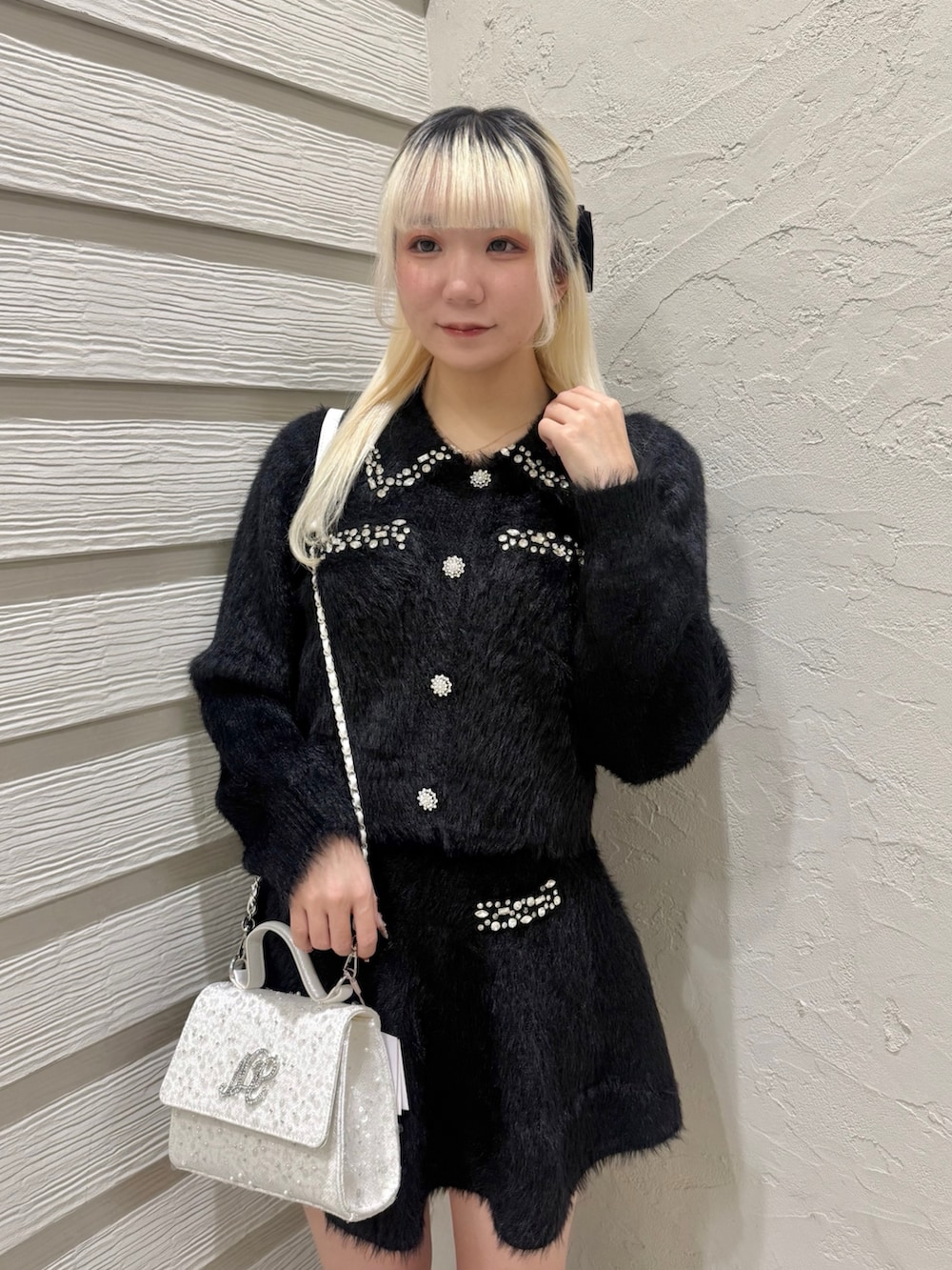 ブラック系のセットアップ、ホワイト系のショルダーバッグ、ブラック系のブーツを着用したレディースの冬コーディネートの4枚目の写真