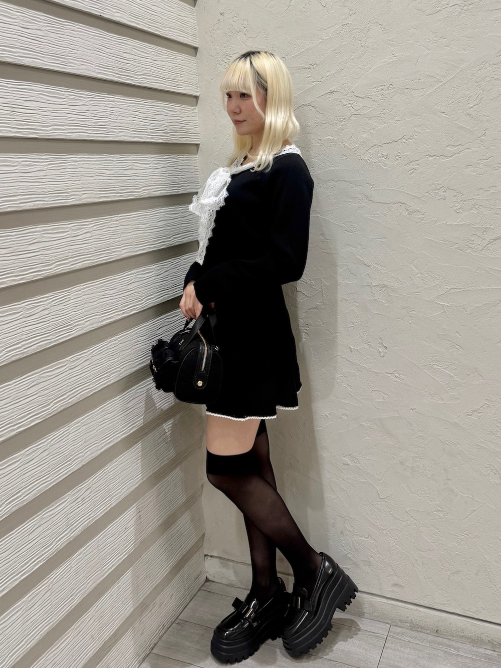 ブラック系のセットアップ、ブラック系のショルダーバッグ、ブラック系のローファーを着用したレディースの冬コーディネートの2枚目の写真