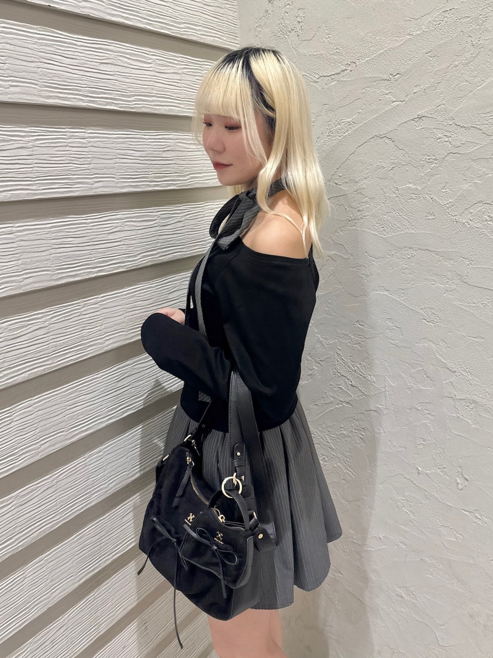 ブラック系のショルダーバッグ、グレー系のスカート、ブラック系のTシャツ/カットソーを着用したレディースの冬コーディネートの5枚目の写真