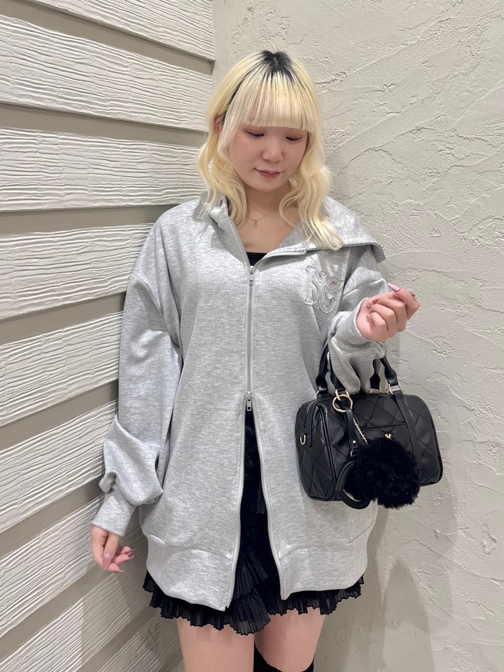 グレー系のパーカー、ブラック系のキャミソール、ブラック系のスカートを着用したレディースの冬コーディネートの5枚目の写真