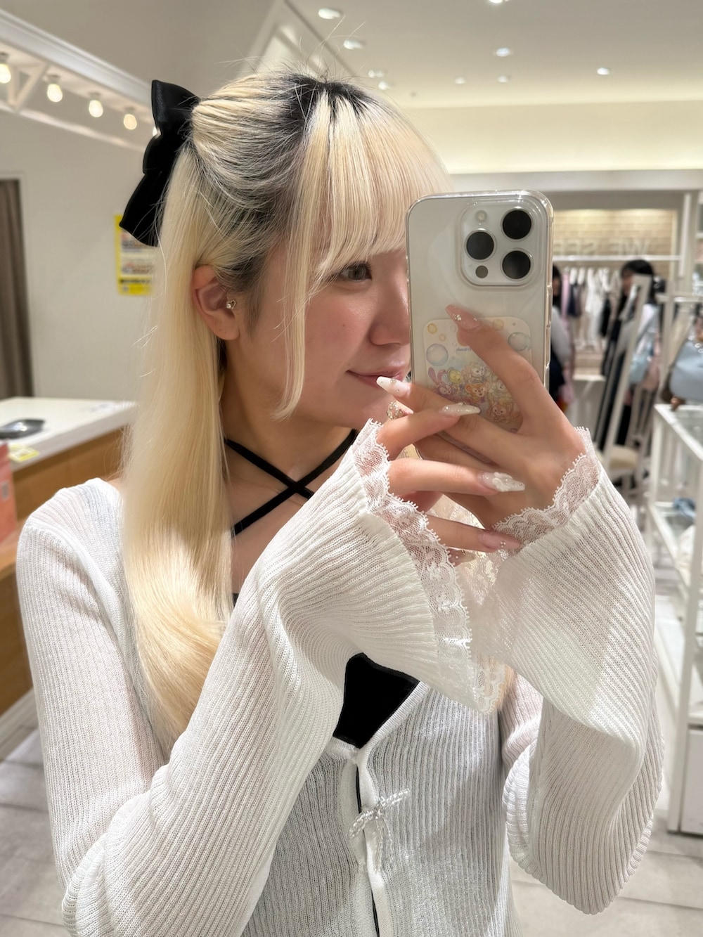 ホワイト系のカーディガン/ボレロ、ブラック系のワンピース、ホワイト系のサンダルを着用したレディースの春コーディネートの5枚目の写真