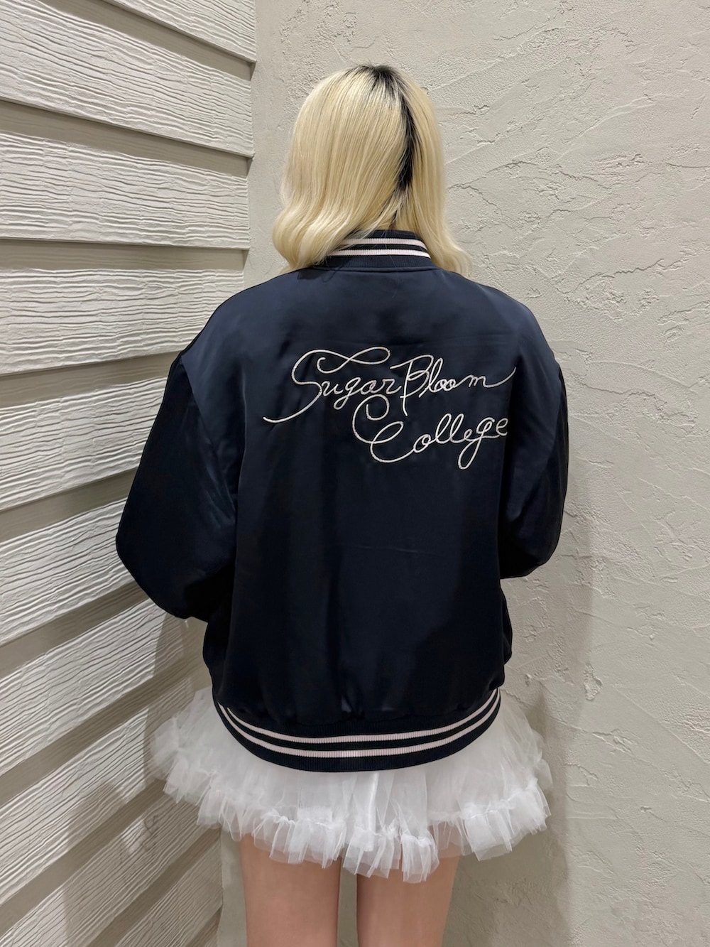 ブルー系のスカジャン、ホワイト系のスカート、ブラック系のスニーカーを着用したレディースの冬コーディネートの6枚目の写真