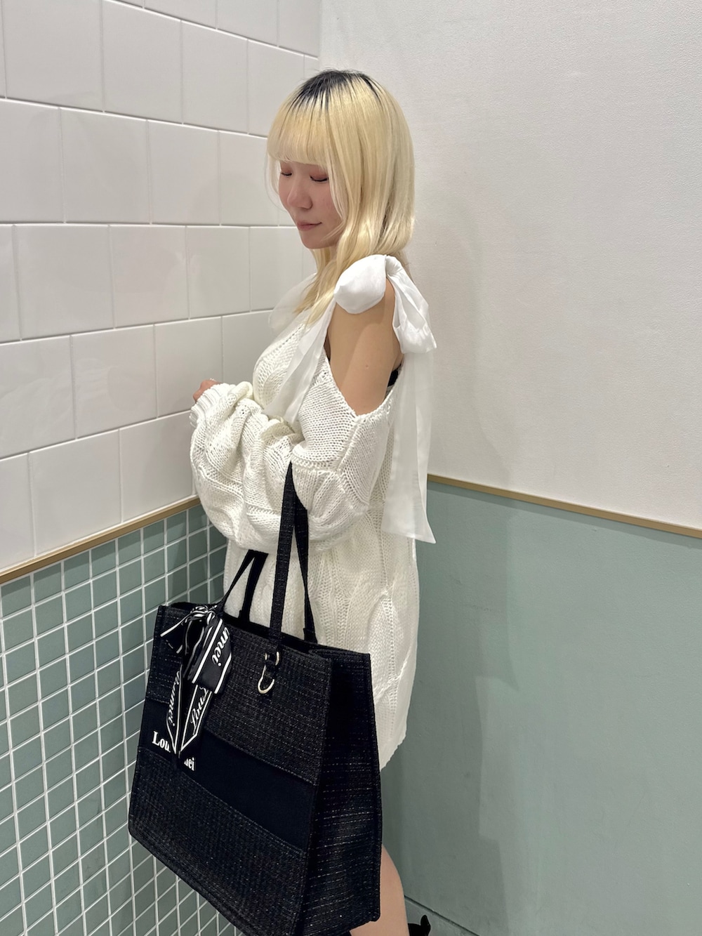 ブラック系のトートバッグ、ブラック系のブーツ、ホワイト系のワンピースを着用したレディースの冬コーディネートの6枚目の写真