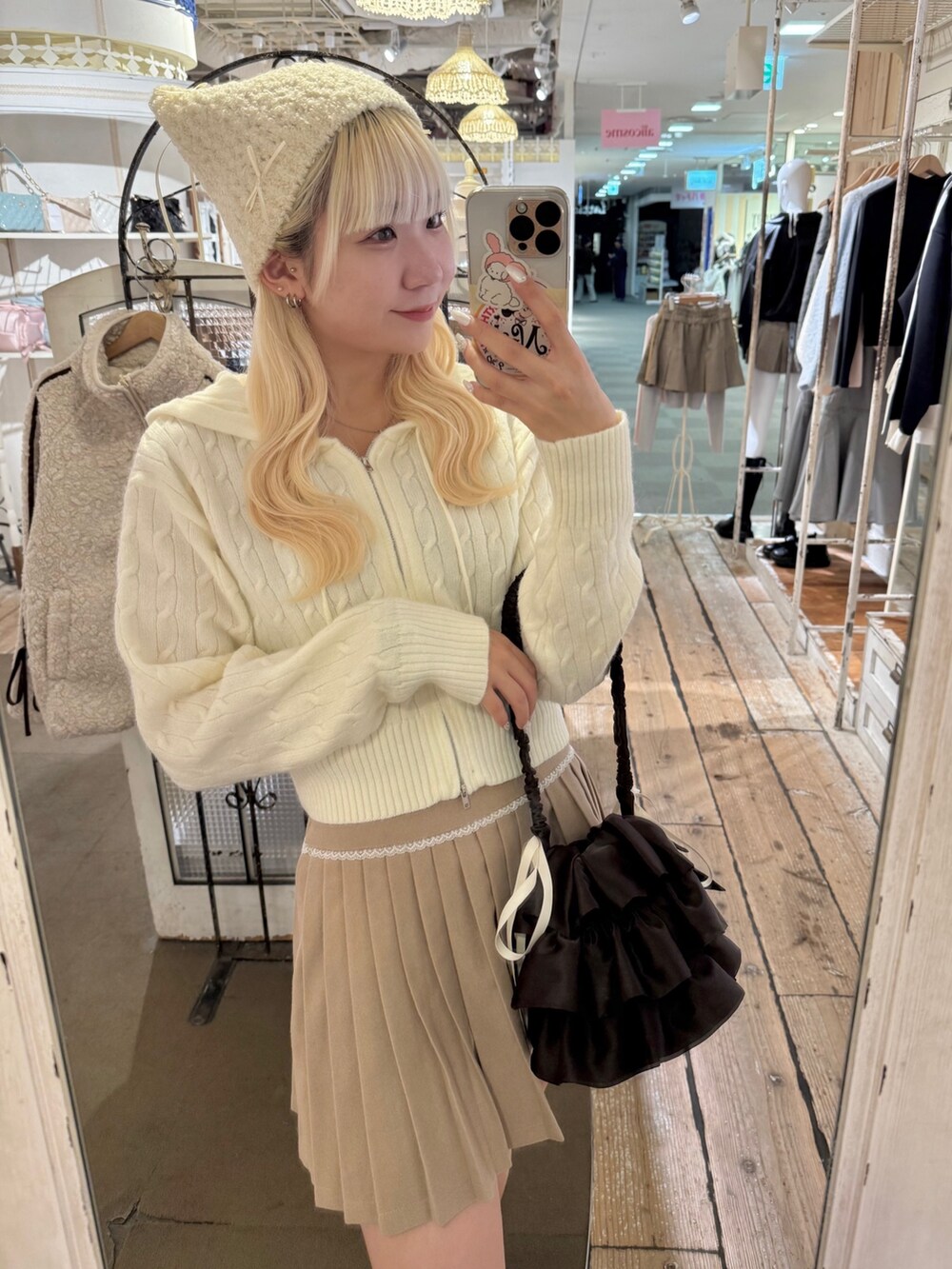 ベージュ系のスカート、ホワイト系のパーカー、ブラウン系のブーツを着用したレディースの秋コーディネートの2枚目の写真