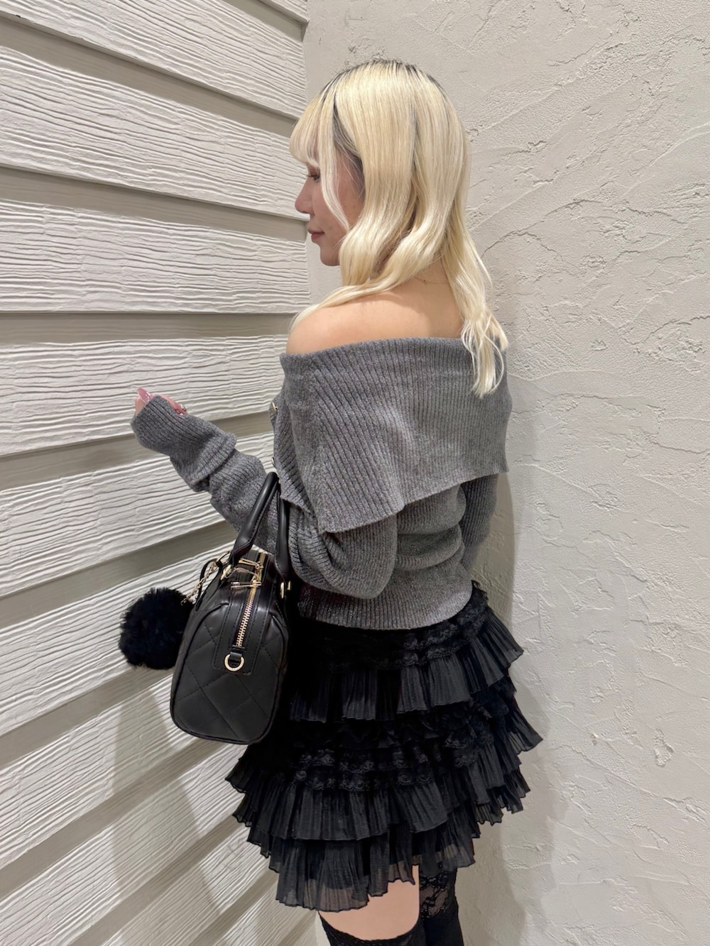 グレー系のニット/セーター、ブラック系のスカート、ブラック系のボストンバッグを着用したレディースの冬コーディネートの5枚目の写真