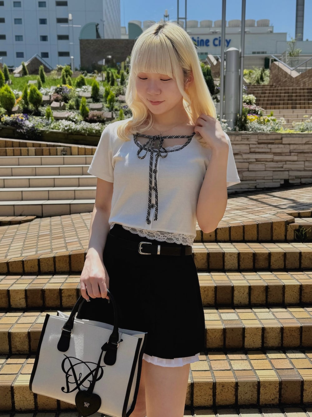 ブラック系のスカート、ホワイト系のTシャツ/カットソー、ホワイト系のトートバッグを着用したレディースの夏コーディネートの3枚目の写真