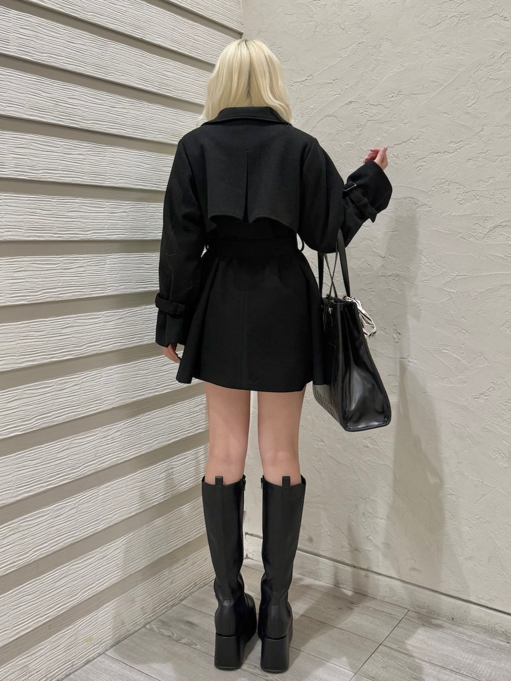 ブラック系のチェスターコート、ブラック系のトートバッグ、ホワイト系のアンサンブルを着用したレディースの冬コーディネートの3枚目の写真