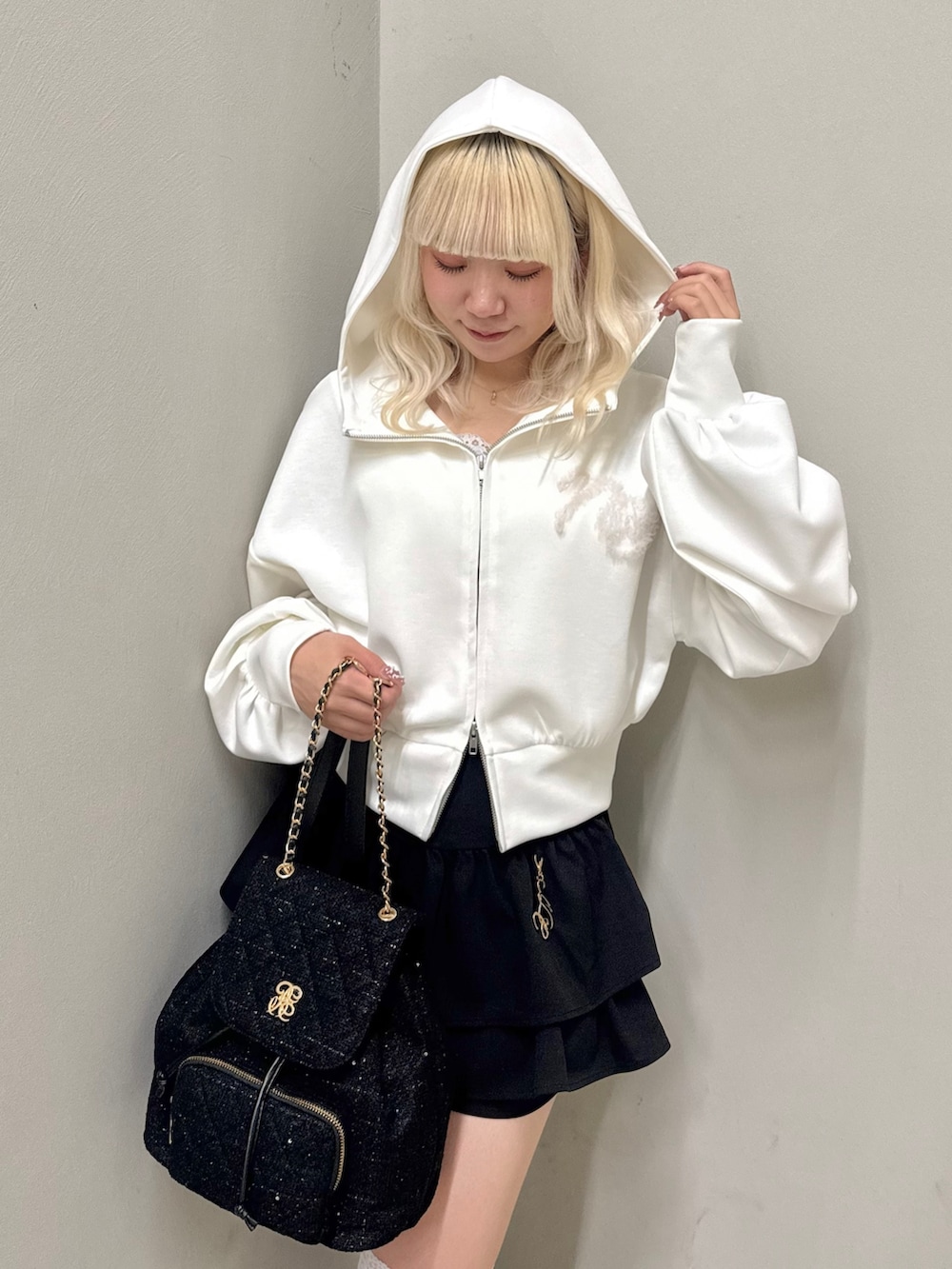 ホワイト系のパーカー、ブラック系のスカート、ブラック系のバックパック/リュックを着用したレディースの春コーディネートの5枚目の写真