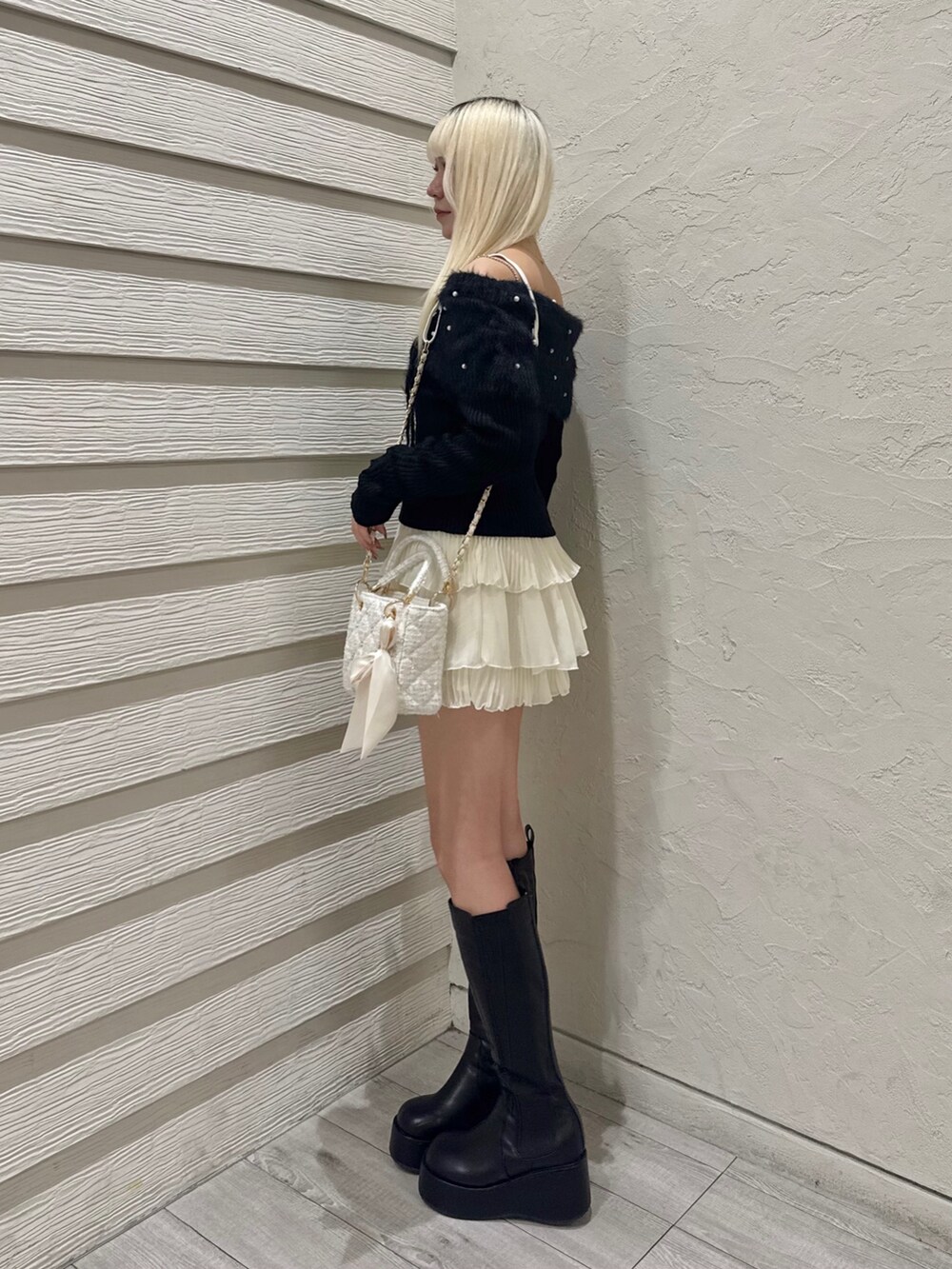 ブラック系のニット/セーター、ホワイト系のスカート、ホワイト系のショルダーバッグを着用したレディースの冬コーディネートの3枚目の写真