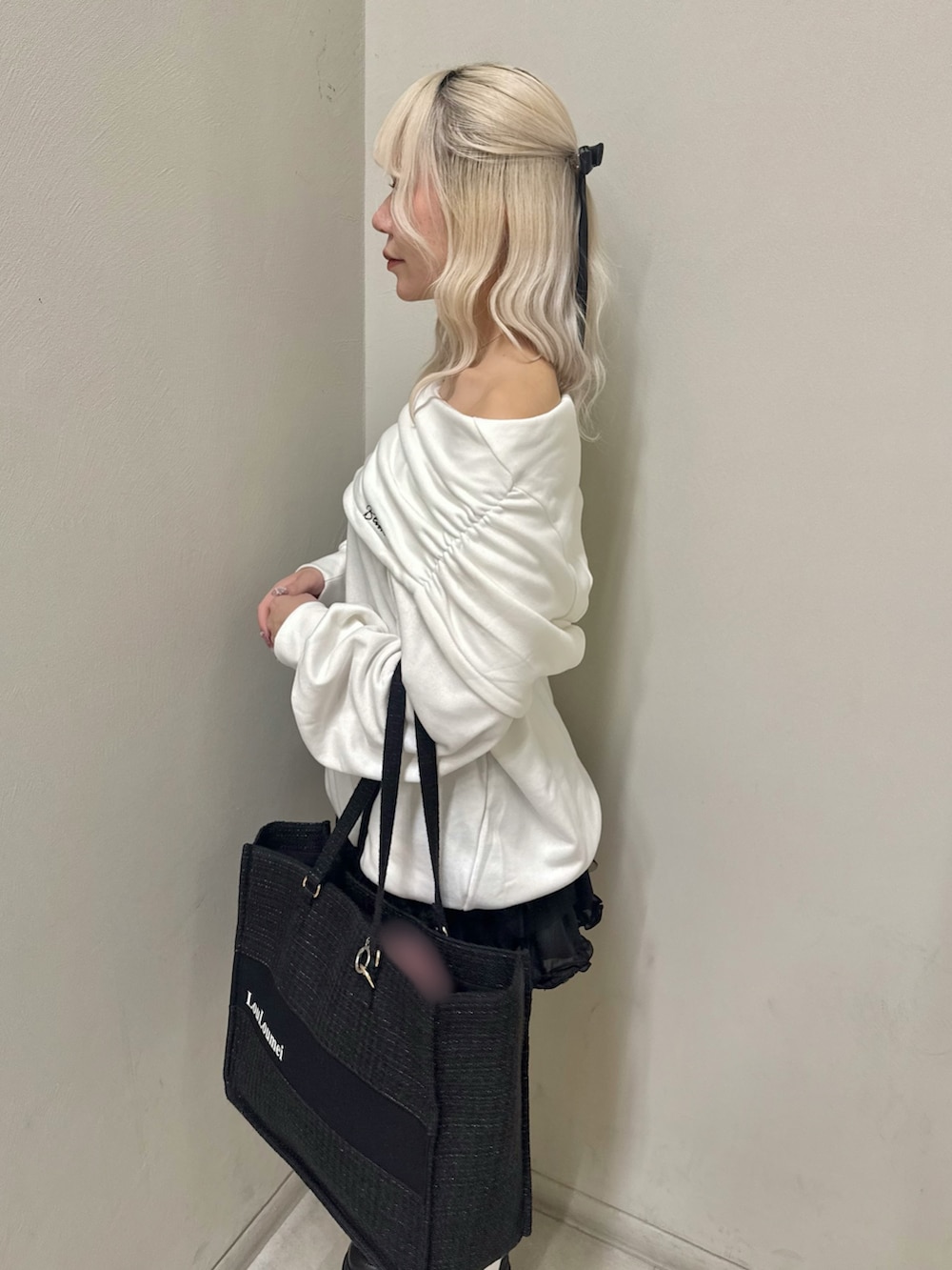 ホワイト系のパーカー、ブラック系のトートバッグ、ブラック系のスカートを着用したレディースの春コーディネートの5枚目の写真