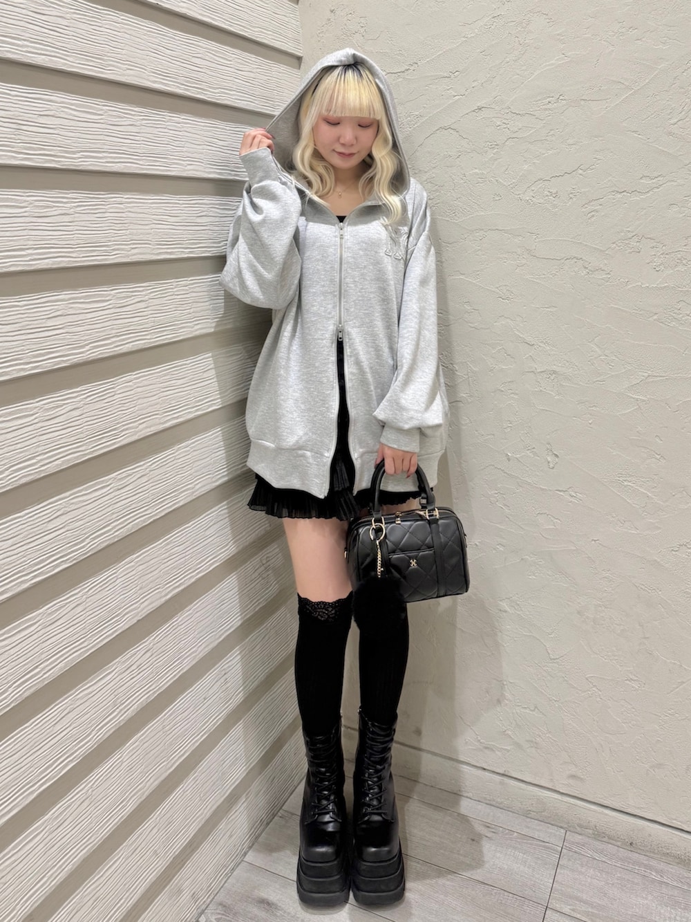グレー系のパーカー、ブラック系のキャミソール、ブラック系のスカートを着用したレディースの冬コーディネートの4枚目の写真