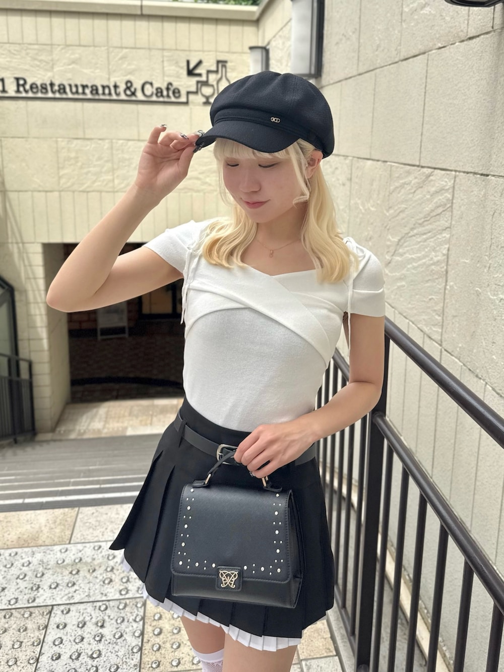 ブラック系のスカート、ホワイト系のTシャツ/カットソー、ブラック系のショルダーバッグを着用したレディースの春コーディネートの3枚目の写真