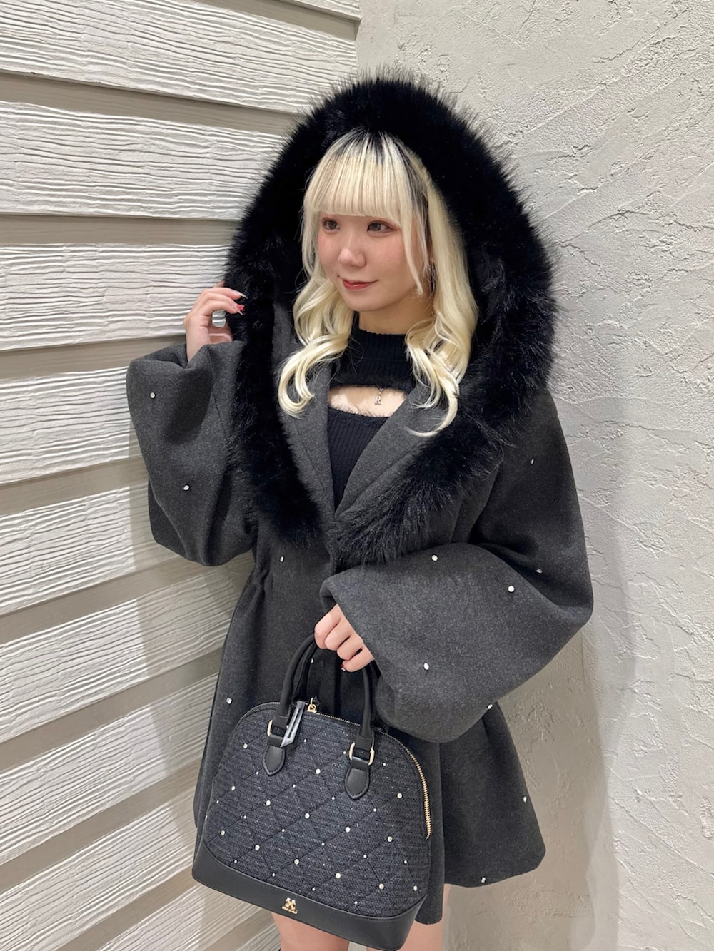 グレー系のその他アウター、ブラック系のニット/セーター、ブラック系のハンドバッグを着用したレディースの冬コーディネートの4枚目の写真