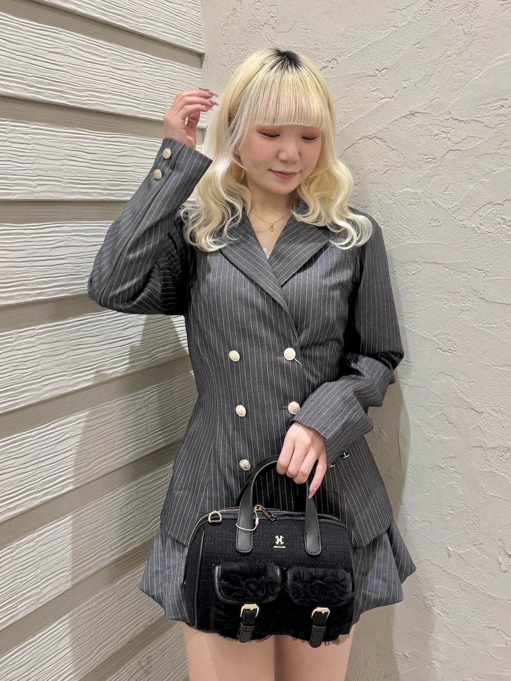 グレー系のテーラードジャケット、グレー系のスカート、ブラック系のショルダーバッグを着用したレディースの冬コーディネートの4枚目の写真