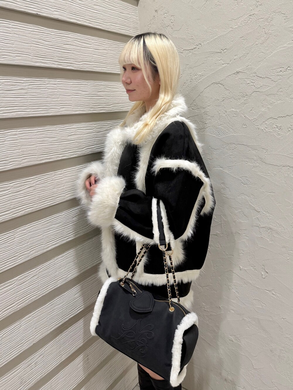 ブラック系のブーツ、ブラック系のボストンバッグ、ブラック系のスカートを着用したレディースの冬コーディネートの5枚目の写真