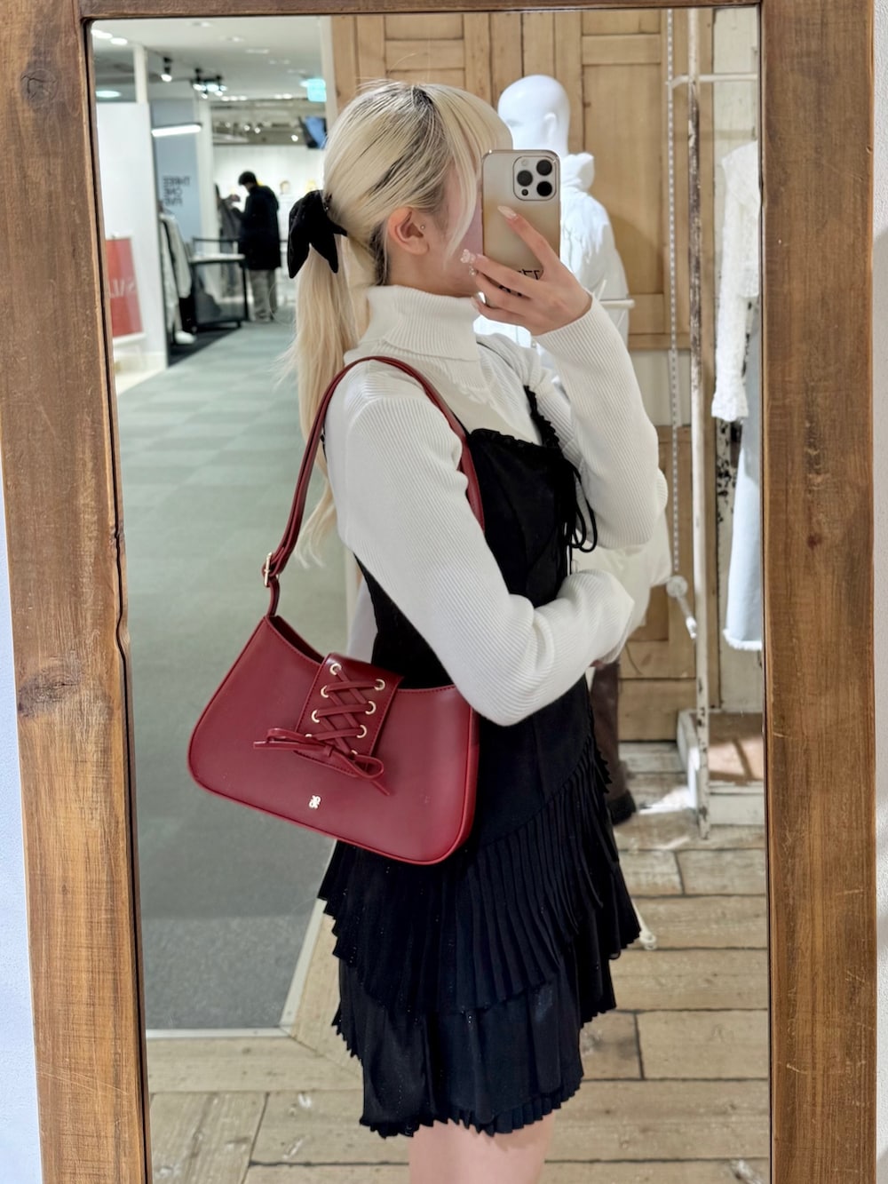 レッド系のショルダーバッグ、ブラック系のワンピース、ホワイト系のニット/セーターを着用したレディースの冬コーディネートの3枚目の写真