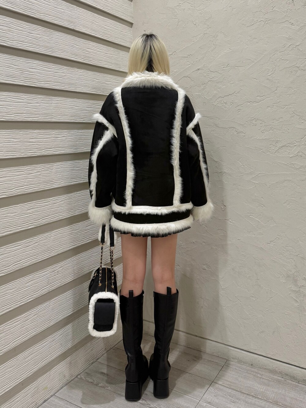 ブラック系のブーツ、ブラック系のボストンバッグ、ブラック系のスカートを着用したレディースの冬コーディネートの3枚目の写真