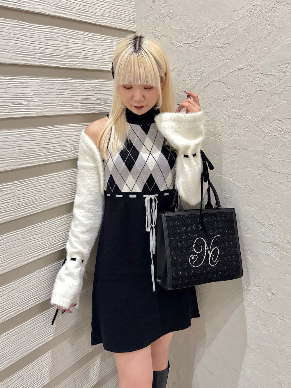 ブラック系のトートバッグ、ブラック系のワンピース、ブラック系のブーツを着用したレディースの秋コーディネートの4枚目の写真